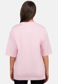 T-shirt rose clair, coupe oversize, manches courtes, en coton doux, col rond, sans motifs ni accents visibles.