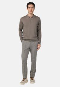 Siva rebrasta polo majica s dolgimi rokavi in gumbi, v kombinaciji s svetlosivimi elegantnimi hlačami in kremnimi supergami z rjavimi poudarki.