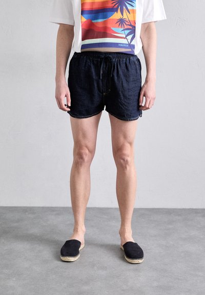 Dunkelblaue Jeansshorts mit elastischem Bund und Kordelzug. Lockere Passform, abgerundeter Saum, kombiniert mit einem Grafikt-Shirt und schwarzen Espadrilles.