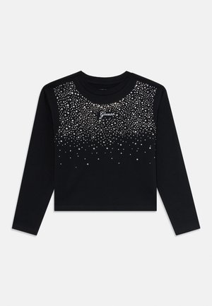 Schwarzes, langärmliges Cropped-Top mit verstreuten silbernen Nieten auf der Vorderseite und weißem "Guess"-Logo, das zentriert unter dem Ausschnitt platziert ist.