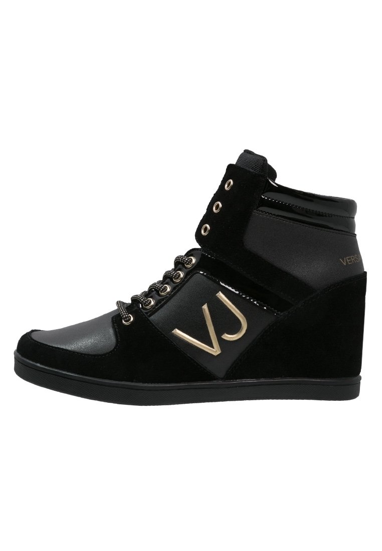 Baskets montantes noires avec un talon compensé, présentant un mélange de daim et de cuir verni, des détails dorés, un laçage à l'avant et une sangle en Velcro.