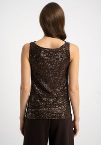Brązowy top z cekinami o okrągłym dekolcie i bez rękawów. Materiał jest błyszczący, dopasowany, sięgający do talii.
