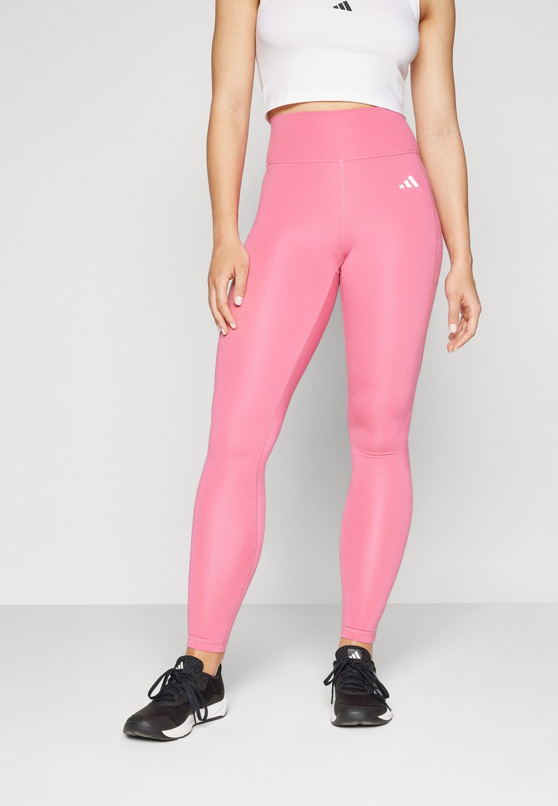 Ružové legíny s vysokým pásom vyrobené z elastického materiálu s hladkou textúrou, s jemným prešívaním a bielym logom Adidas.