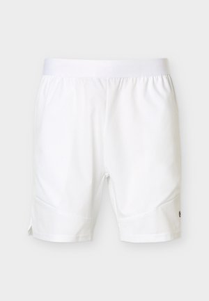 Yksinkertaiset valkoiset urheilushortsit, joissa on joustava vyötärönauha ja pieni logo toisen lahkeen alareunassa neutraalilla taustalla.