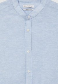 Camicetta azzurro chiaro a maniche corte con colletto a banda e pattina frontale con bottoni. Realizzata in un tessuto morbido e testurizzato, etichettata "Comfort Fit."