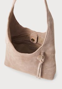 Sac à épaule en daim dans un taupe doux. Présente une finition texturée, une longue bandoulière et un accent de breloque à frange avec un charme doré. L'intérieur dispose d'une poche zippée.