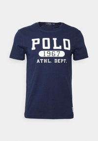 Navy blue cotton T-shirt with short sleeves. Features bold white text: "POLO 1967 ATHL. DEPT." in a casual style. Round neck design.