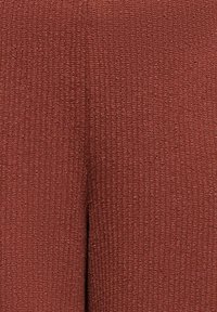 Κοντινή λήψη υφής πλεκτού υφάσματος σε ζεστή καμένη πορτοκαλί απόχρωση με ορατό κατακόρυφο ριμπ ύφασμα.