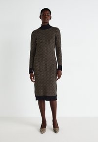 Vestido de malha com um padrão geométrico em dourado sobre um fundo preto, com um decote alto, mangas longas e bainha e punhos canelados.