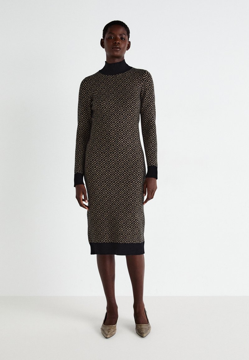 Vestido de malha com um padrão geométrico em dourado sobre um fundo preto, com um decote alto, mangas longas e bainha e punhos canelados.