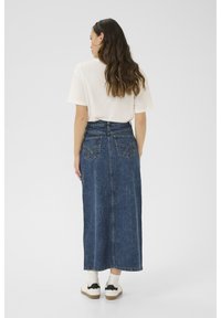 jeans maxi krilo v temno modri barvi z dvema zadnjima žepoma, v kombinaciji z lahkim majico in belimi supergami z črnimi detajli.