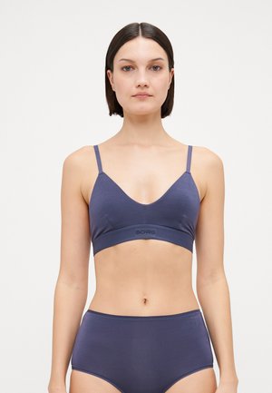 Navy blue wireless bralette with adjustable thin straps and a wide textured band featuring logo. Smooth fabric with a seamless design.