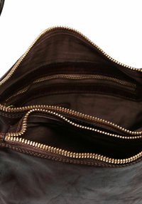 Interno di una borsa in pelle marrone con diversi scomparti con zip e zip in tonalità oro. Texture liscia e design strutturato.