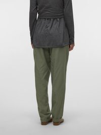 Tumesinise tooniga, pika varrukaga pluus, mille seljal on kogutud detail, kombineeritud lahtiste oliivroheliste pükstega. Mõlemad riided on valmistatud pehmest, kergest kangast.