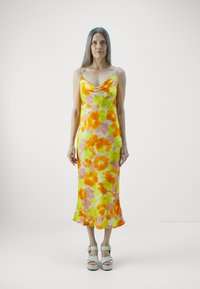 Blomstrete slip-kjole i gule, oransje og rosa nyanser, med cowl-hals og tynne stropper. Glatt stoff faller til midt på leggen.