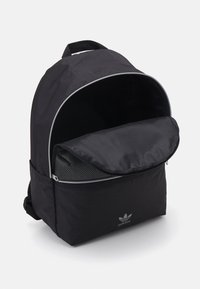 Black backpack with a rounded top, zipper closure, and mesh pocket. Features a subtle logo on the front and a smooth, durable fabric.