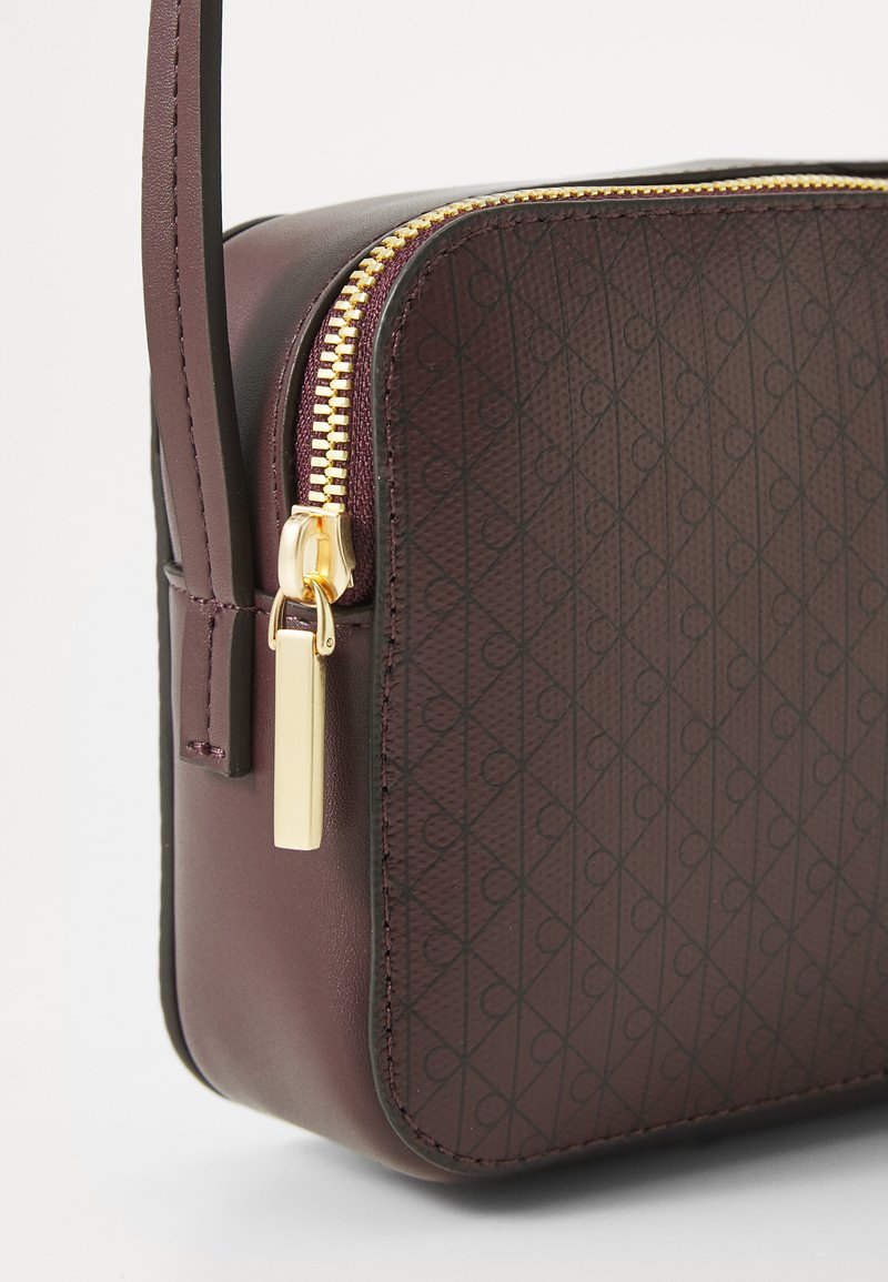 Burgunderfarbene Handtasche mit einem glatten Lederkörper, strukturiertem Diamantmuster, goldfarbenem Reißverschluss und rechteckigem Hardware-Detail an der Seite.