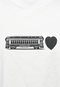 Illustrazione di un filobus nero con dettagli lineari e testo "CARHARTT WIP", accanto a una semplice forma di cuore nero su sfondo di tessuto bianco.