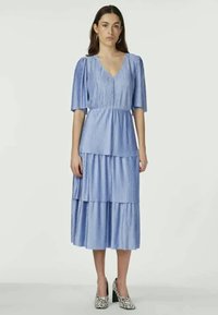 Ανοιχτό μπλε, πλισέ μίντι φόρεμα με κοντά μανίκια, v-λαιμόκοψη, επιμερισμένο σχέδιο και λεία υφή. Συνδυασμένο με παπούτσια τακουνιού με σχέδιο.