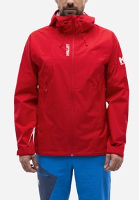 Veste imperméable rouge avec capuche ajustée, fermeture éclair à l'avant et poches latérales. Comprend des poignets ajustables et un logo réfléchissant sur la manche.