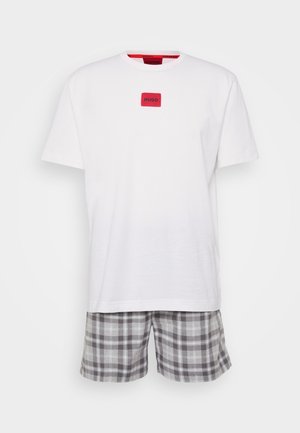 T-shirt branca de algodão com logotipo quadrado vermelho, combinada com calções às riscas cinzentos e pretos, apresentando um cós elástico e um corte confortável.
