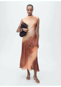 Lang, mouwloos jurk in een verloop van warme oranje en bruine tinten, gemaakt van lichtgewicht stof; accessorized met een donkere geweven clutch.