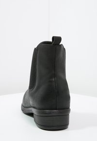 Stivaletto in pelle nera con pannelli elastici laterali, texture liscia, punta tonda e un lembo sul tallone per facilitare la calzata.