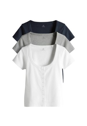 Trzy krótkie topy z prążkowanej dzianiny z guzikami z przodu, w kolorach białym, szarym i granatowym, ułożone jedna na drugiej i wycentrowane na białym tle.