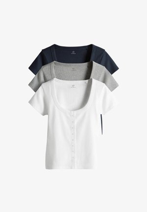 Trzy krótkie topy z prążkowanej dzianiny z guzikami z przodu, w kolorach białym, szarym i granatowym, ułożone jedna na drugiej i wycentrowane na białym tle.