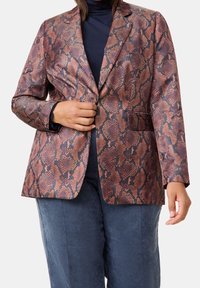 Blazer imprimé serpent marron et noir avec une fermeture à un bouton, des revers crantés et deux poches avant. Texture lisse et coupe ajustée.