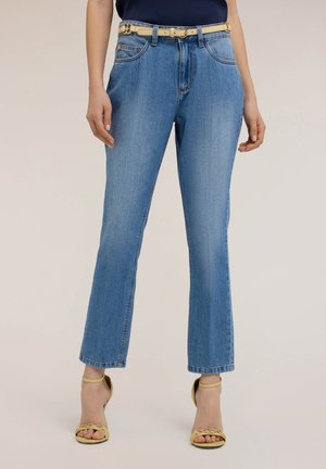 Lichtblauwe denim straight-leg jeans met een hoge taille, vijf zakken en een beige riem met een ronde gesp. Accenten zijn gele hakken.