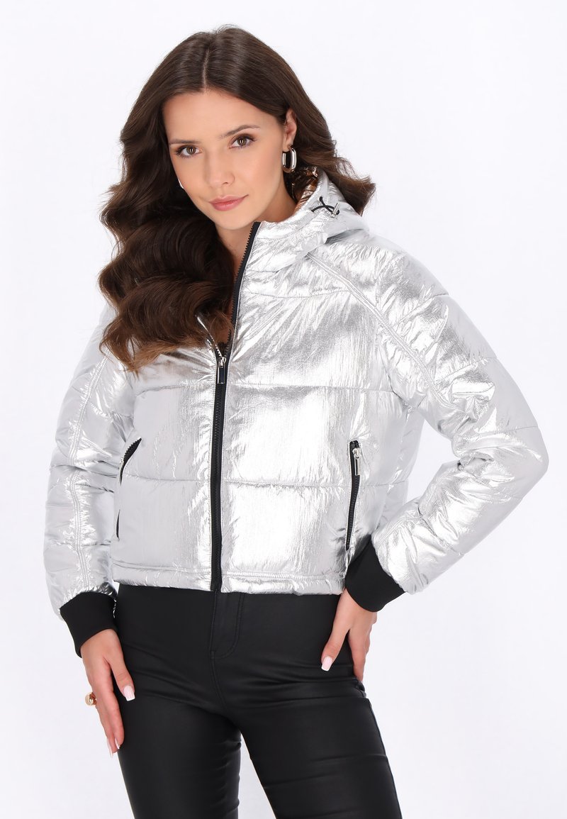Giacca puffer argentata con finitura lucida, chiusura frontale con zip, tasche laterali e dettagli neri ai polsini e all'orlo. Design con cappuccio.