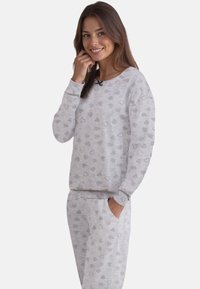 Harmaa pyjama-setti, jossa on sydänkuvioita. Settiin kuuluu pitkähihainen pyjamatoppi, jossa on pyöreä kaula-aukko, sekä yhteensopivat housut, joissa on taskut ja joustava vyötärö.
