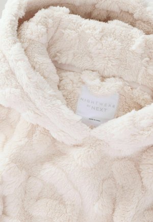 Svetlo béžová plyšová mikina s kapucňou, vyrobená z mäkkého, textúrovaného materiálu s vystúpenými vzormi. Štítok uvádza "NIGHTWEAR by NEXT."