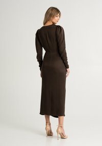 Braunes, langärmliges Kleid mit tailliertem Oberteil und leicht gepufften Schultern. Hergestellt aus einem strukturierten Stoff, der bis zur Mitte der Wade reicht und mit einem Rückenverschluss versehen ist.