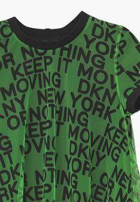 Zelené síťované tričko s výrazným černým textem "DKNY NEW YORK KEEP IT MOVING", s černým kulatým výstřihem a krátkými rukávy.