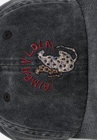 Gorra de tela gris oscuro con un diseño bordado de dos animales manchados y texto rojo formando un patrón circular alrededor de ellos.