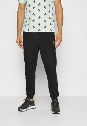 Pantalons de jogging noirs avec des poignets élastiques et un petit logo. Associés à une chemise à manches courtes vert menthe avec un motif répété.