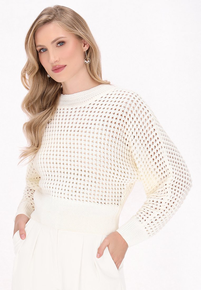 Suéter blanco de punto con un tejido suelto, que presenta un cuello y puños acanalados. El diseño incluye una longitud corta y un patrón texturizado.