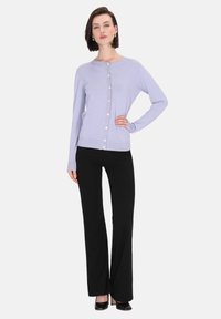 Ljus lila cardigan med rund halsringning, knappöppning fram och långa ärmar, matchad med svarta utsvängda byxor och svarta klackskor.