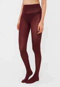 Burgundy strumpbyxor med en genomskinlig finish och hög midja; slät textur, helängd täckning och tåfri skärning vid anklarna.