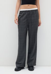 Grijze geruite broeken met een losse pasvorm, voorzien van een elastische tailleband met een koord. De stof heeft een soepele textuur en een wijd beenontwerp.