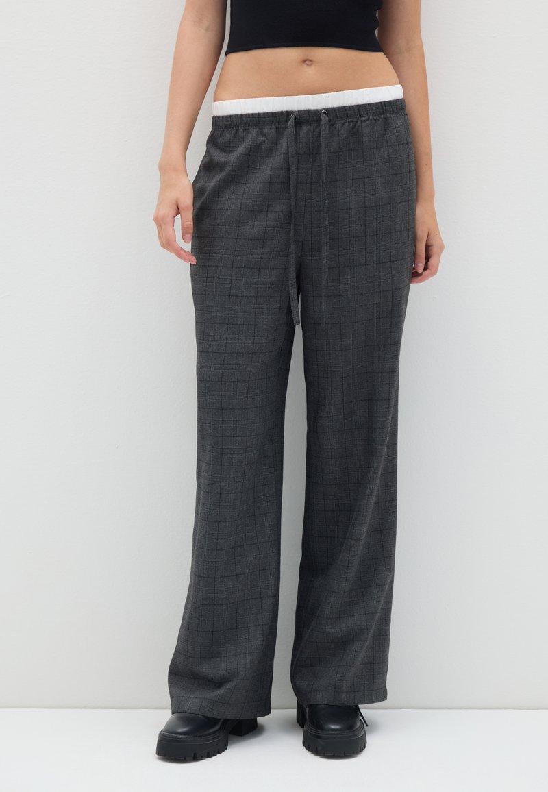 Grijze geruite broeken met een losse pasvorm, voorzien van een elastische tailleband met een koord. De stof heeft een soepele textuur en een wijd beenontwerp.