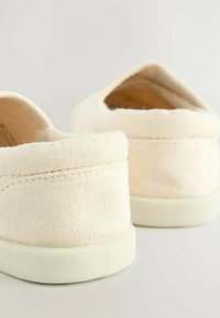 Beige Leinenschlupfschuhe mit rundem Zeh, weichem Futter und leichten Gummisohlen. Sichtbare Nähte am Obermaterial.