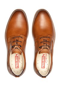 Zapatos de vestir de cuero marrón con punteras redondeadas, diseño de cordones y detalles perforados en las plantillas. Acabado suave y costura en contraste.