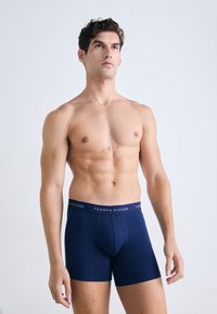 Tengerészkék boxeralsó, márkázott elasztikus derékpánttal, rajta "TOMMY HILFIGER" felirattal fehér színben. Nyújtható anyagból készült, testhez simuló fazon, sima tapintás.