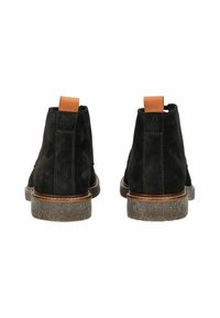 Stivaletti neri in suede con un'accensione in pelle marrone sul tallone, suola in gomma grigia chiara a contrasto e dettagli di cucitura sui lati.