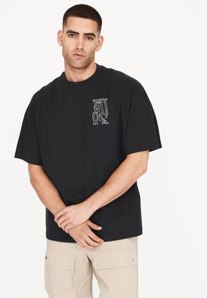 Camiseta de algodón negra con un estampado gráfico en blanco. El diseño incluye elementos abstractos y texto en la zona del pecho izquierdo.