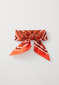 Rød bomullsbandana med svarte blomster- og geometriske mønstre, med spisse ender og en knute i midten. Lett og strukturert.
