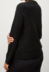 Schwarzer Strickpullover mit lockerer Passform, rundem Ausschnitt und geripptem Saum. Hat lange Ärmel und einen weichen, strukturierten Stoff.